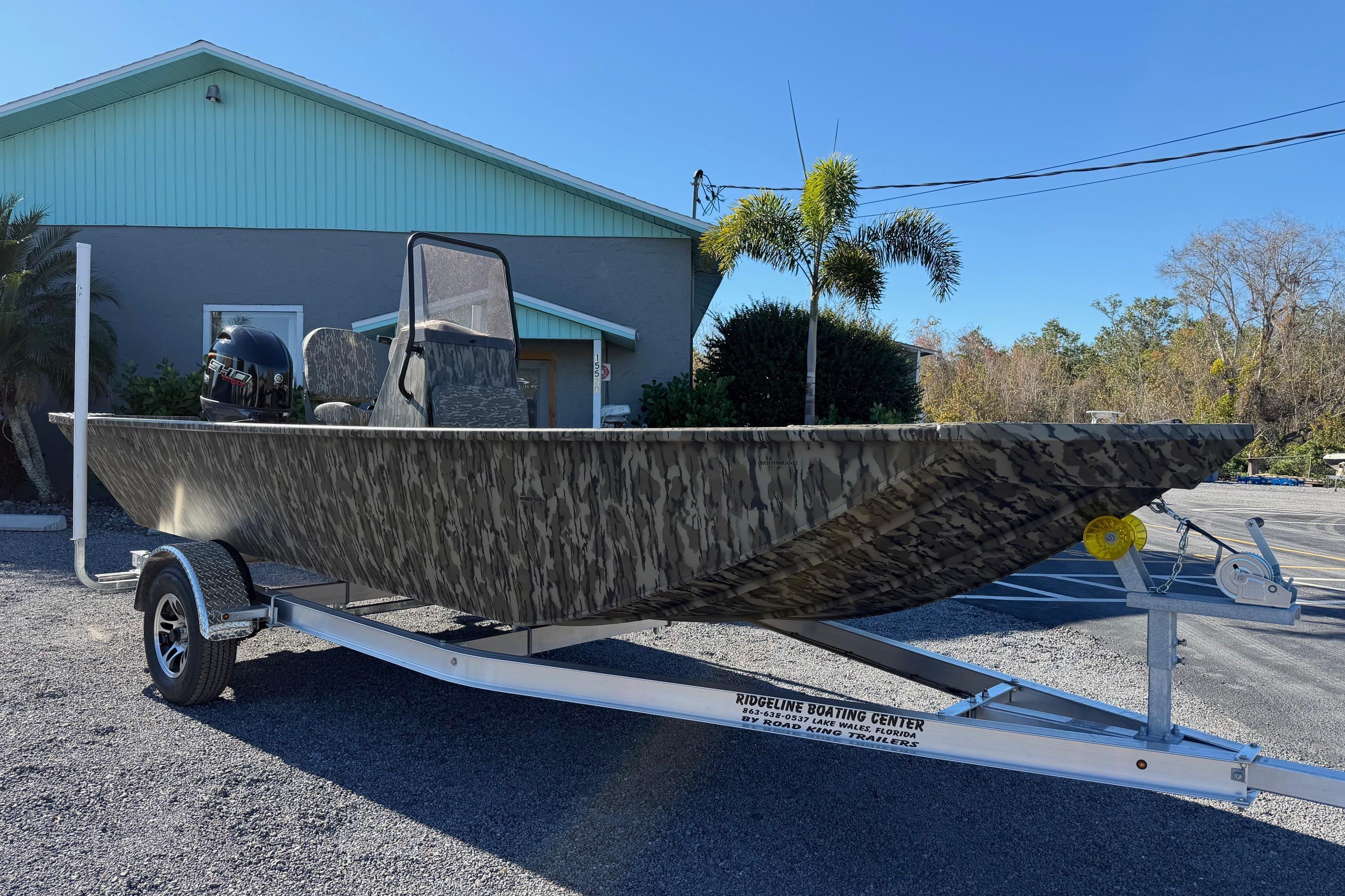2026 Smoker Craft Sportsman 1866 boat on trailer, camo design, parked outdoors.