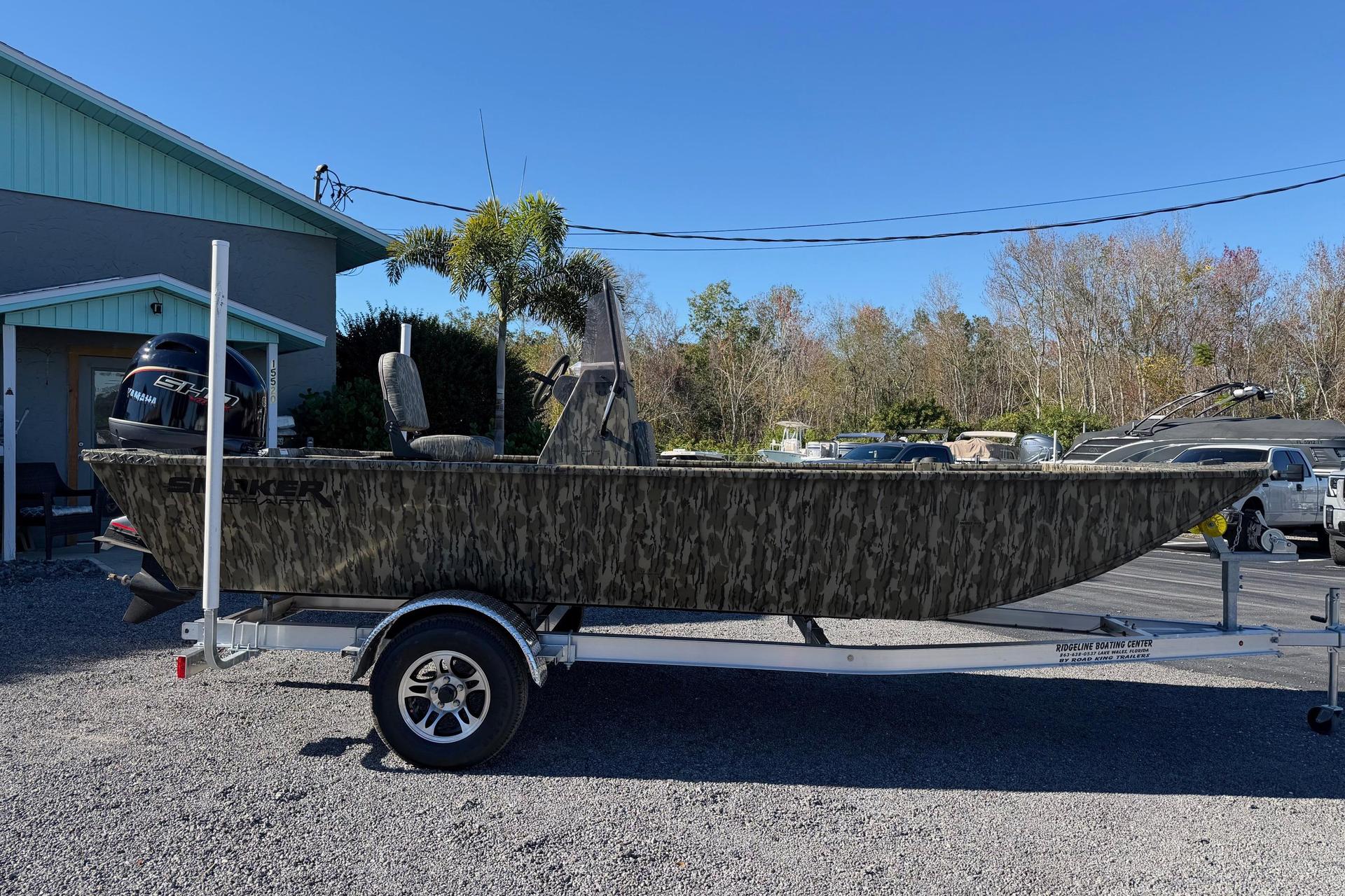 2026 Smoker Craft Sportsman 1866 boat on trailer, camo design, parked outdoors.