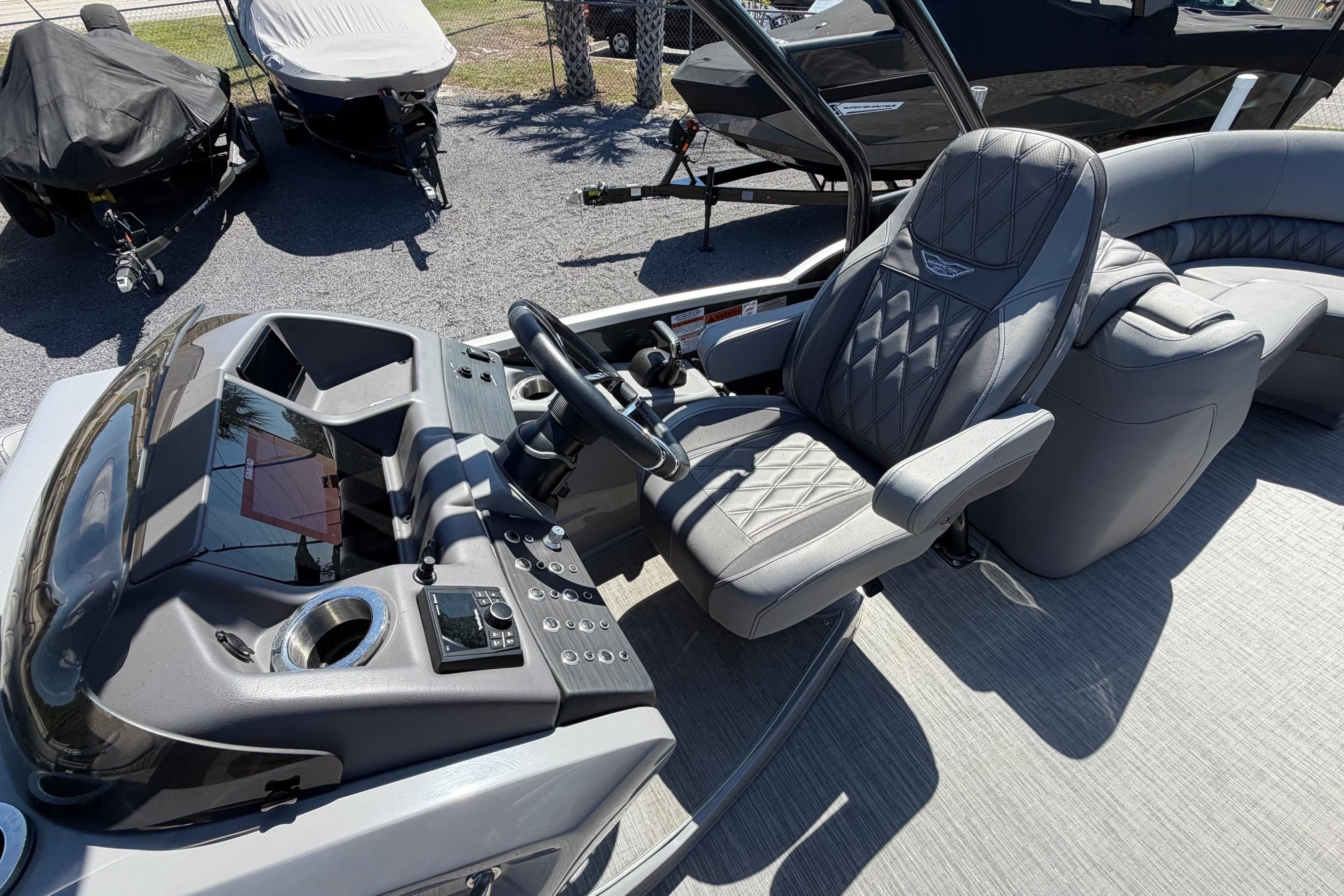 2022 Bennington 25 QX boat interior with luxurious captain's chair and modern dashboard.