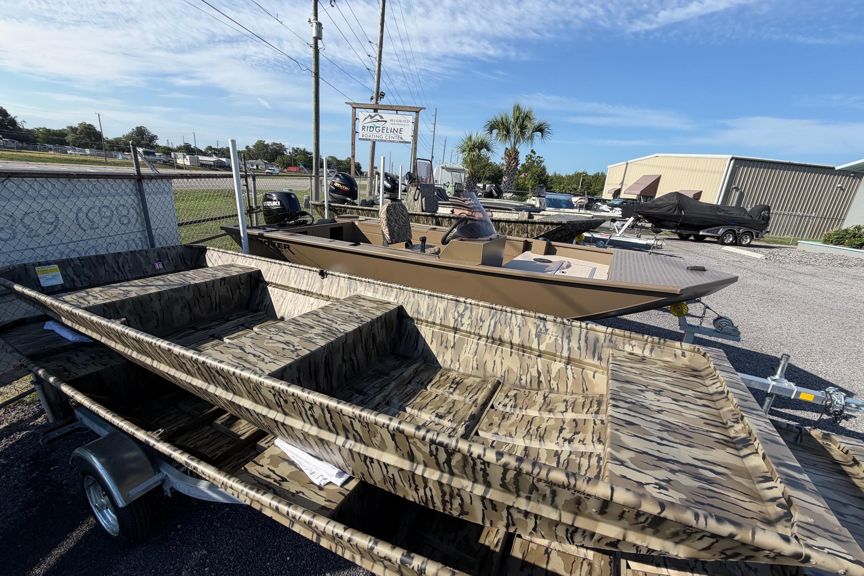 2026 Smoker Craft 1432 Jon boat with camouflage design on a trailer at a dealership.